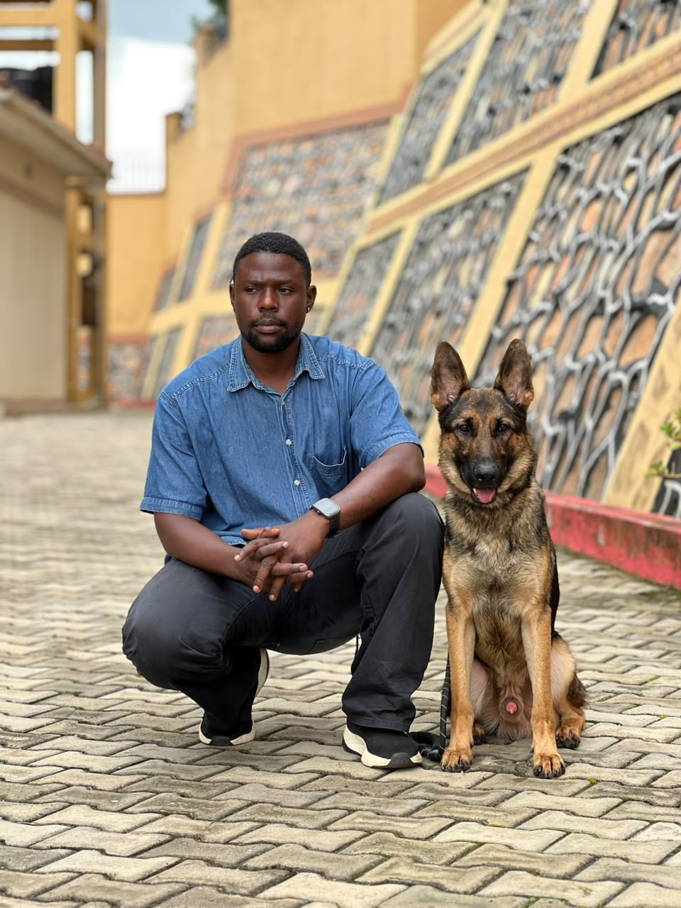 Handler kneeling beside a German Shepherd at the academy